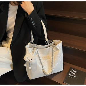 Close-up of white tote bag featuring snake pattern leather and pearl chain detail
