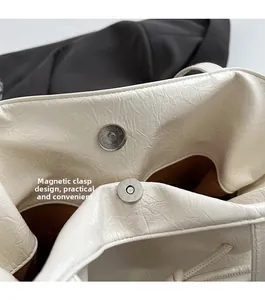Vue détaillée de la fermeture magnétique et du cuir blanc texturé du sac fourre-tout