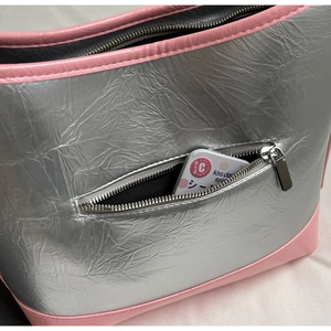 Detail of silver metallic tote bag with pink trim and functional exterior zipper pocket