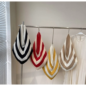 Detail of four colorful striped crochet knit tote bags hanging on a display wall