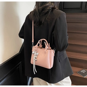 Detail of pink lychee leather bucket bag with silver bow charm and detachable strap