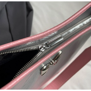 Close-up of pink leather piping and silver metallic bow detail on the grey shoulder bag
