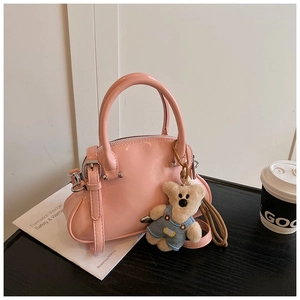 Detalle de bolso rosa con colgante de oso de peluche sobre escritorio de madera