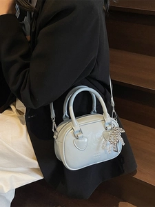 Light blue pillow handbag with silver bead charm shown in a stylish crossbody look