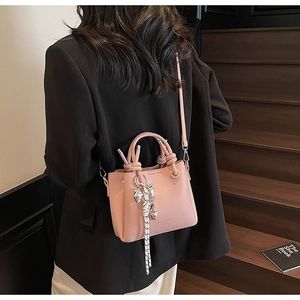 Pink lychee leather bucket bag detail with woven rope and silver bow charm