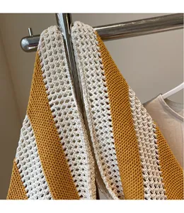 Macro detail of hand-knitted tote bag with hollow mesh pattern and yellow striped texture