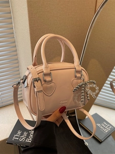 Pink glossy patent leather handbag with heart detail and pearl bow charm accessory