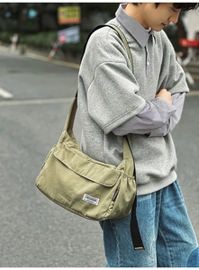 Street style shot of olive green messenger bag with CHUANGMI label and black strap