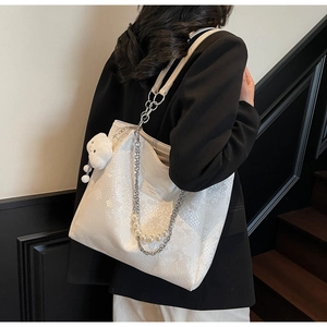 Detail of white snakeskin tote bag with pearl chain and rabbit charm on model