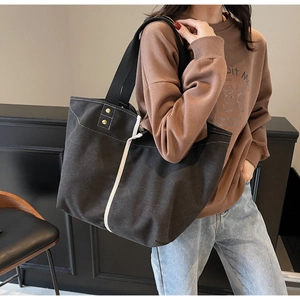 Detailed shot of large black canvas tote bag with white stripes on female model