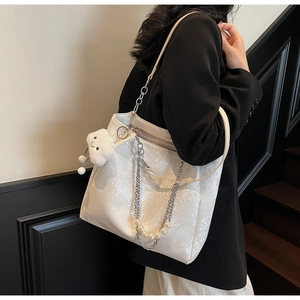 Detail of white snakeskin tote bag with silver chain, pearl charms and plush cloud pendant