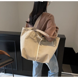 Detail view of large canvas tote bag showing contrast vertical stripe and metal rivet accents