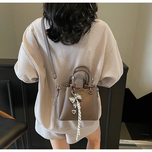 Detail of dark brown leather bucket bag with silver bow and heart charm pendants