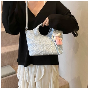 Gros plan du sac seau plissé bleu clair avec pendentif ours porté par un mannequin
