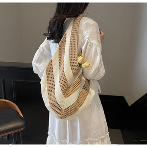 Close-up of knit tote bag featuring beige and white V-shaped stripes on shoulder