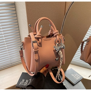 Pink bucket bag with lychee texture featuring a silk scarf handle and bow charm detail