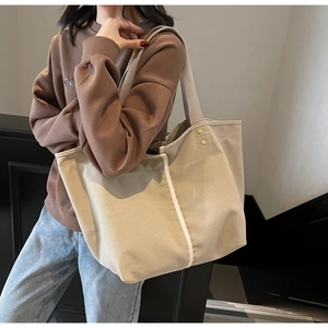 Detailed shot of beige canvas tote bag showing side gold rivet and durable handle straps