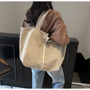 Detailed back view of a large canvas tote bag with gold rivets and reinforced stitching