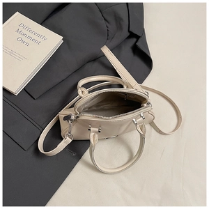Detalle del bolso concha de cuero beige con cierre de cremallera y compartimento