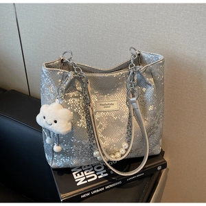 Detail of silver snake-print tote bag with pearl handle and plush cloud charm