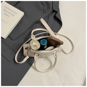 Vista interior del pequeño bolso crema con perfume, lápiz labial y un smartphone