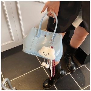 Detail of light blue patent leather tote bag with white fluffy cloud charm on handle