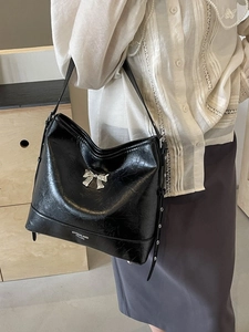 Chic black cracked leather shoulder bag with a silver metal bow charm for women