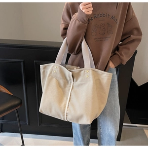 Detail of durable beige canvas tote bag with reinforced rivets and wide shoulder strap