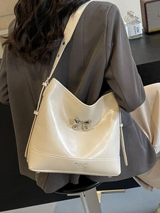 Chic cream bow shoulder bag with pleated texture and adjustable strap in urban setting