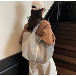 Close-up of grey canvas tote bag showing golden rivet reinforcements and durable straps