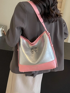 Silver metallic hobo bag with pink trim and bow detail shown on shoulder of a model