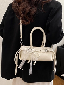 Borsa Boston beige con fiocco in pizzo e nappe di perle mostrata come borsa a tracolla