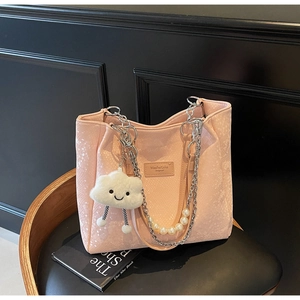 Detail of pink snake-pattern tote bag with pearl chain strap and cloud plush charm
