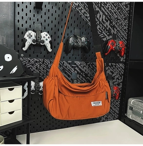 Detail view of orange nylon dumpling bag featuring side pocket and brand logo label