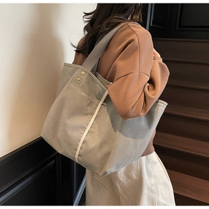 Detail of sage green canvas tote bag featuring beige straps and reinforced gold rivets