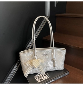 Gros plan sur sac bandoulière argenté à motif serpent avec pendentif perle et logo