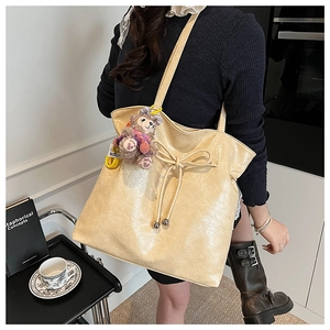 Détail d'un sac cabas beige avec texture plissée et cordon de serrage en ruban