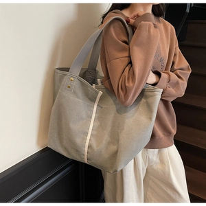 Detail shot of the large canvas tote bag with grey straps and reinforced gold rivets