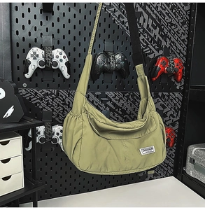 Detail view of light green crescent nylon crossbody bag on a dark pegboard display