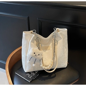 Detail of cream snakeskin tote bag with pearl chain strap and plush cloud charm