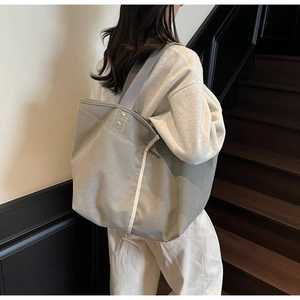 Detail view of large grey canvas tote bag with cream stripes and golden rivets