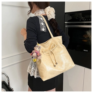 Détail du sac cabas blanc crème en cuir brillant texturé avec décoration de nœud