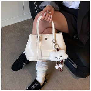 White glossy patent leather handbag with fluffy cloud charm shown by model in casual style
