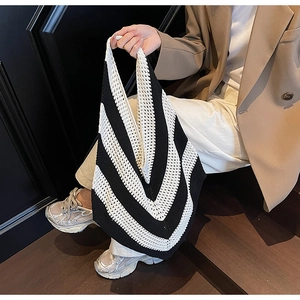 Detail of the knit tote bag featuring black and white stripes and a classic V-shaped cut
