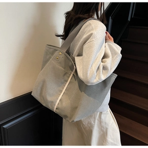 Detail of grey canvas tote bag with reinforced gold rivets and wide shoulder strap