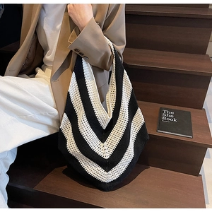 Close-up of black and white V-stripe knit tote bag with detailed woven texture on shoulder