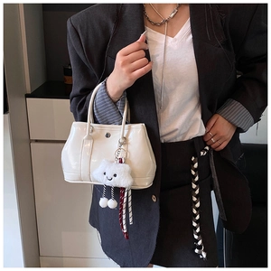 Close-up of white patent leather handbag featuring a cute plush cloud charm detail