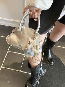 Bolso de mano plateado metalizado con amuleto de osito para el estilo primavera 2026