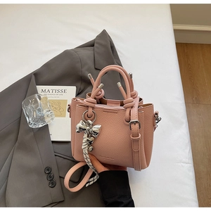 Detail view of pink bucket bag with knotted handle and silver butterfly charm