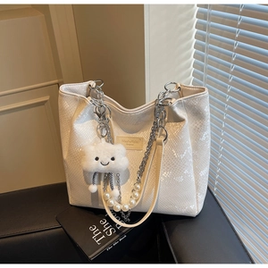 Detail of white snakeskin tote with pearl chain, metal strap and plush cloud charm
